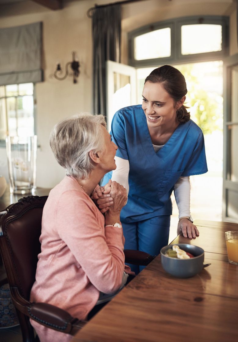 Caregiver checking on a senior woman at breakfast